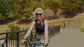 Mujer joven bonita que sonríe mientras que monta su bicicleta en día de verano soleado en slomo metrajes Mujer joven bonita que sonríe mientras que monta su bicicleta en día de verano soleado en slomo metrajes