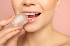 Mujer joven con el cubo de hielo en fondo del color imágenes de archivo libres de regalías Mujer joven con el cubo de hielo en fondo del color imágenes de archivo libres de regalías