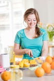 Mujer joven de la aptitud que bebe el smoothie anaranjado en cocina fotografía de archivo libre de regalías Mujer joven de la aptitud que bebe el smoothie anaranjado en cocina fotografía de archivo libre de regalías