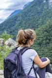 Mujer joven del caminante que se sienta en una roca con la mochila Fotos de archivo Mujer joven del caminante que se sienta en una roca con la mochila Fotos de archivo