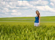 Mujer joven despreocupada feliz en un campo de trigo verde Foto de archivo Mujer joven despreocupada feliz en un campo de trigo verde Foto de archivo