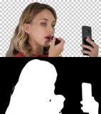 Mujer joven elegante hermosa que aplica la barra de labios roja en los labios y que mira la pantalla del teléfono, Alpha Channel imágenes de archivo libres de regalías Mujer joven elegante hermosa que aplica la barra de labios roja en los labios y que mira la pantalla del teléfono, Alpha Channel imágenes de archivo libres de regalías