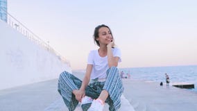 Mujer joven hermosa en la ropa ligera del verano que se sienta en el embarcadero en el puerto en el amanecer La hembra cauc?sica metrajes Mujer joven hermosa en la ropa ligera del verano que se sienta en el embarcadero en el puerto en el amanecer La hembra cauc?sica metrajes