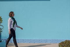 Mujer joven hermosa que camina más allá de un abucheo que lleva de la pared de ladrillo azul imagen de archivo Mujer joven hermosa que camina más allá de un abucheo que lleva de la pared de ladrillo azul imagen de archivo