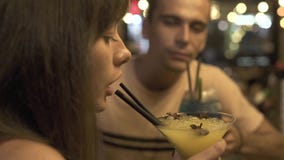 Mujer joven que bebe de hombre alcohólico del cóctel de la paja junto en club nocturno Junte el cóctel de consumición del hombre almacen de metraje de vídeo Mujer joven que bebe de hombre alcohólico del cóctel de la paja junto en club nocturno Junte el cóctel de consumición del hombre almacen de metraje de vídeo