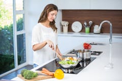 Mujer joven que cocina el alimento foto de archivo Mujer joven que cocina el alimento foto de archivo