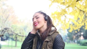 Mujer joven que escucha la música en los auriculares y el baile almacen de metraje de vídeo Mujer joven que escucha la música en los auriculares y el baile almacen de metraje de vídeo