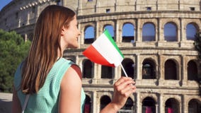 Mujer joven que se coloca cerca de Colosseum en Roma, Italia Adolescente que agita la bandera italiana en la cámara lenta almacen de metraje de vídeo Mujer joven que se coloca cerca de Colosseum en Roma, Italia Adolescente que agita la bandera italiana en la cámara lenta almacen de metraje de vídeo