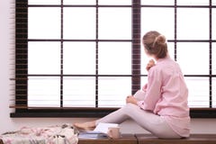 Mujer joven que se relaja cerca de ventana con las persianas en casa imagen de archivo libre de regalías Mujer joven que se relaja cerca de ventana con las persianas en casa imagen de archivo libre de regalías