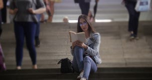 Mujer joven que se sienta en las escaleras en el subterráneo y que lee un libro metrajes Mujer joven que se sienta en las escaleras en el subterráneo y que lee un libro metrajes