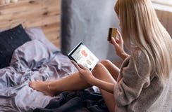 Mujer joven que tiene compras en línea en dormitorio imagen de archivo libre de regalías Mujer joven que tiene compras en línea en dormitorio imagen de archivo libre de regalías