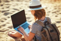 Mujer joven que trabaja con el ordenador port?til en la naturaleza en playa fotografía de archivo Mujer joven que trabaja con el ordenador port?til en la naturaleza en playa fotografía de archivo