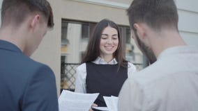 Mujer joven y dos hombres en desgaste formal que discuten documentos en la terraza La muchacha que da los papeles a los colegas metrajes Mujer joven y dos hombres en desgaste formal que discuten documentos en la terraza La muchacha que da los papeles a los colegas metrajes
