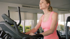 Mujer juguetona activa apta que hace ejercicios en velosimulator Usando su smartwatch que comprueba vitals almacen de video Mujer juguetona activa apta que hace ejercicios en velosimulator Usando su smartwatch que comprueba vitals almacen de video