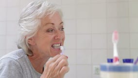 Mujer mayor en dientes de cepillado del cuarto de baño metrajes Mujer mayor en dientes de cepillado del cuarto de baño metrajes