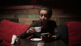 Mujer negra que bebe smartphones calientes del café y del uso metrajes Mujer negra que bebe smartphones calientes del café y del uso metrajes