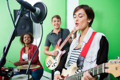 Mujer que canta mientras que banda que juega Musical imagen de archivo Mujer que canta mientras que banda que juega Musical imagen de archivo