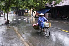 Mujer que completa un ciclo en un día lluvioso en hoi un Vietnam fotografía de archivo libre de regalías Mujer que completa un ciclo en un día lluvioso en hoi un Vietnam fotografía de archivo libre de regalías