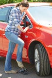 Mujer que infla el neumático del coche con la bomba de pie foto de archivo Mujer que infla el neumático del coche con la bomba de pie foto de archivo