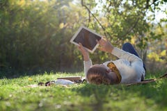 Mujer que miente en lecho en hierba verde con el ipad fotografía de archivo Mujer que miente en lecho en hierba verde con el ipad fotografía de archivo