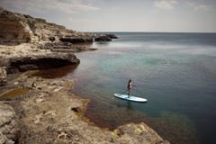 Mujer que se bate en tablero del SORBO en un mar foto de archivo Mujer que se bate en tablero del SORBO en un mar foto de archivo