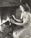 Mujer que se calienta las manos por la chimenea fotografía de archivo Mujer que se calienta las manos por la chimenea fotografía de archivo
