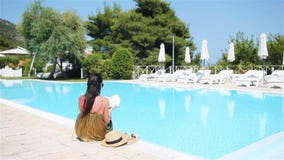 Mujer que se relaja por la piscina en un centro turístico del hotel de lujo que disfruta de vacaciones perfectas del día de fiest metrajes Mujer que se relaja por la piscina en un centro turístico del hotel de lujo que disfruta de vacaciones perfectas del día de fiest metrajes