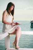 Mujer que se sienta en obstáculo cerca del mar, libro de lectura Imágenes de archivo libres de regalías Mujer que se sienta en obstáculo cerca del mar, libro de lectura Imágenes de archivo libres de regalías