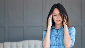 Mujer que sufre de la tensión o un dolor de cabeza que hace muecas en dolor en casa almacen de metraje de vídeo Mujer que sufre de la tensión o un dolor de cabeza que hace muecas en dolor en casa almacen de metraje de vídeo