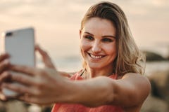 Mujer que toma el selfie que se coloca en la playa fotos de archivo libres de regalías Mujer que toma el selfie que se coloca en la playa fotos de archivo libres de regalías