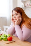 Mujer regordeta triste que piensa en su dieta foto de archivo Mujer regordeta triste que piensa en su dieta foto de archivo