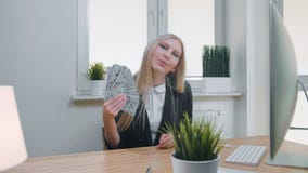 Mujer relajada con el dinero en oficina Hembra rubia joven elegante en el traje de negocios que se sienta en el escritorio con el metrajes Mujer relajada con el dinero en oficina Hembra rubia joven elegante en el traje de negocios que se sienta en el escritorio con el metrajes