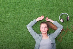 Mujer relajada que escucha la música con los auriculares que mienten en hierba Foto de archivo Mujer relajada que escucha la música con los auriculares que mienten en hierba Foto de archivo