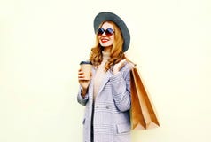 Mujer sonriente feliz del retrato con los bolsos de compras, sosteniendo la taza de café, capa rosada que lleva, sombrero redondo fotografía de archivo libre de regalías Mujer sonriente feliz del retrato con los bolsos de compras, sosteniendo la taza de café, capa rosada que lleva, sombrero redondo fotografía de archivo libre de regalías