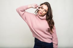 Mujer sonriente feliz joven en la camisa a cuadros que hace la victoria, positivo, signo de la paz en su ojo en fondo gris fotografía de archivo libre de regalías Mujer sonriente feliz joven en la camisa a cuadros que hace la victoria, positivo, signo de la paz en su ojo en fondo gris fotografía de archivo libre de regalías