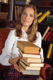 Mujer sonriente que sostiene los libros en la biblioteca imagen de archivo libre de regalías Mujer sonriente que sostiene los libros en la biblioteca imagen de archivo libre de regalías