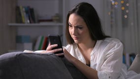 Mujer sospechosa que comprueba el contenido del teléfono en la noche Mujer sospechosa que comprueba el contenido del teléfono en la noche