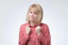 Mujer tímida con el pelo rubio y la mirada seria que mantienen los puños apretados delante de ella que se defiende imagen de archivo Mujer tímida con el pelo rubio y la mirada seria que mantienen los puños apretados delante de ella que se defiende imagen de archivo
