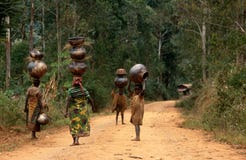 Mujeres y niños que llevan los crisoles en Burundi. fotografía de archivo Mujeres y niños que llevan los crisoles en Burundi. fotografía de archivo