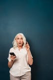 Mulher adulta madura chocada entusiasmado que usa o telefone celular Imagem de Stock Mulher adulta madura chocada entusiasmado que usa o telefone celular Imagem de Stock