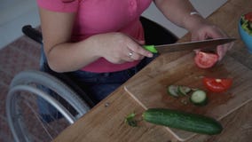 Mulher adulta no tomate do corte da cadeira de rodas para a salada em seu kitche video estoque Mulher adulta no tomate do corte da cadeira de rodas para a salada em seu kitche video estoque