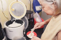 Mulher adulta que põe o arroz branco sobre uma bacia fotografia de stock Mulher adulta que põe o arroz branco sobre uma bacia fotografia de stock