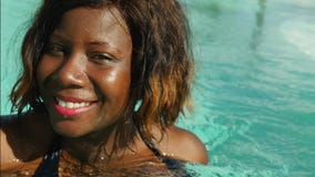 A mulher afro-americana preta feliz e bonita nova no biquini que tem o divertimento na piscina tropical da estância de verão rela video estoque A mulher afro-americana preta feliz e bonita nova no biquini que tem o divertimento na piscina tropical da estância de verão rela video estoque