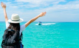 Mulher asiática nova feliz na forma do estilo ocasional com chapéu de palha e trouxa Relaxe e aprecie o feriado na praia tropical fotografia de stock royalty free Mulher asiática nova feliz na forma do estilo ocasional com chapéu de palha e trouxa Relaxe e aprecie o feriado na praia tropical fotografia de stock royalty free