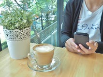 Mulher asiática que trabalha pelo smartphone com xícara de café imagens de stock Mulher asiática que trabalha pelo smartphone com xícara de café imagens de stock