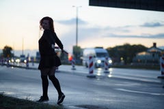 Mulher ativa do dan?arino do viajante que executa em um local da constru??o de estradas no tempo do por do sol com as luzes do ca fotografia de stock royalty free Mulher ativa do dan?arino do viajante que executa em um local da constru??o de estradas no tempo do por do sol com as luzes do ca fotografia de stock royalty free
