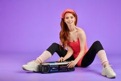 A mulher atlética alegre senta-se após o treinamento da aptidão, desligando o jogador audio portátil imagens de stock A mulher atlética alegre senta-se após o treinamento da aptidão, desligando o jogador audio portátil imagens de stock