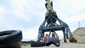 A mulher atlética em uma parte superior cinzenta e em umas caneleiras pretas executa exercícios da força usando uma grande roda d filme A mulher atlética em uma parte superior cinzenta e em umas caneleiras pretas executa exercícios da força usando uma grande roda d filme