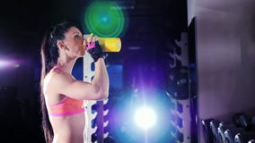 Mulher atlética nova, um halterofilista profissional, bebida da nutrição dos esportes do abanador video estoque Mulher atlética nova, um halterofilista profissional, bebida da nutrição dos esportes do abanador video estoque