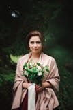 A mulher bonita nova em um vestido de casamento com um ramalhete imagens de stock A mulher bonita nova em um vestido de casamento com um ramalhete imagens de stock